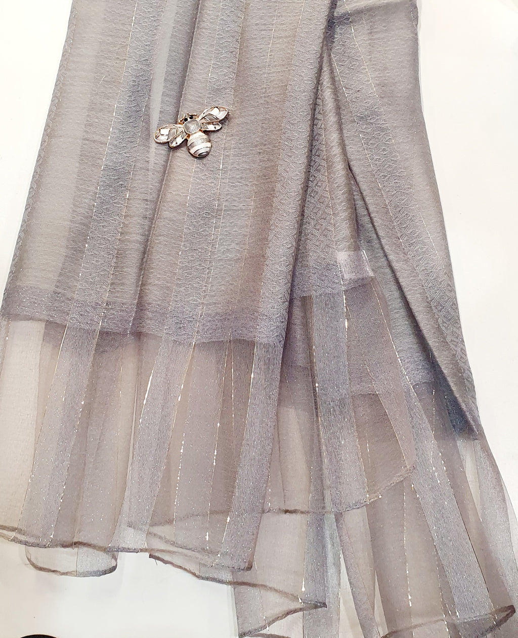 De Éliane is een luxueuze zijden sjaal die zachtheid en elegantie moeiteloos combineert.

De stof, een verfijnde mix van viscose en zijde, voelt soepel en luchtig aan, met een natuurlijke glans die prachtig het licht vangt.
Fijne gouden draadaccenten en een subtiele transparante rand geven de Éliane haar kenmerkende, stijlvolle uitstraling.
Perfect te dragen bij elke gelegenheid — van casual chic tot avondkledij.