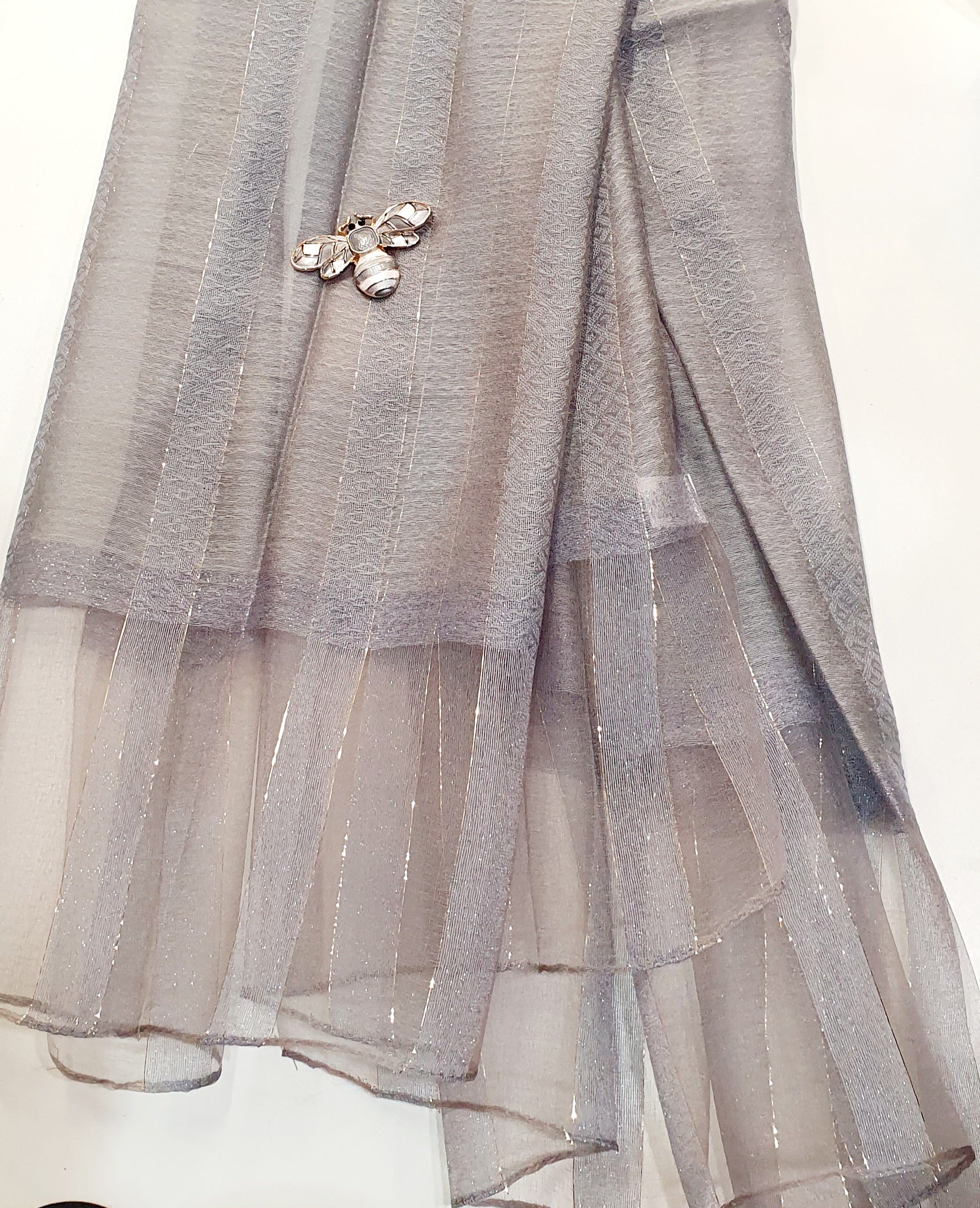 De Éliane is een luxueuze zijden sjaal die zachtheid en elegantie moeiteloos combineert.

De stof, een verfijnde mix van viscose en zijde, voelt soepel en luchtig aan, met een natuurlijke glans die prachtig het licht vangt.
Fijne gouden draadaccenten en een subtiele transparante rand geven de Éliane haar kenmerkende, stijlvolle uitstraling.
Perfect te dragen bij elke gelegenheid — van casual chic tot avondkledij.