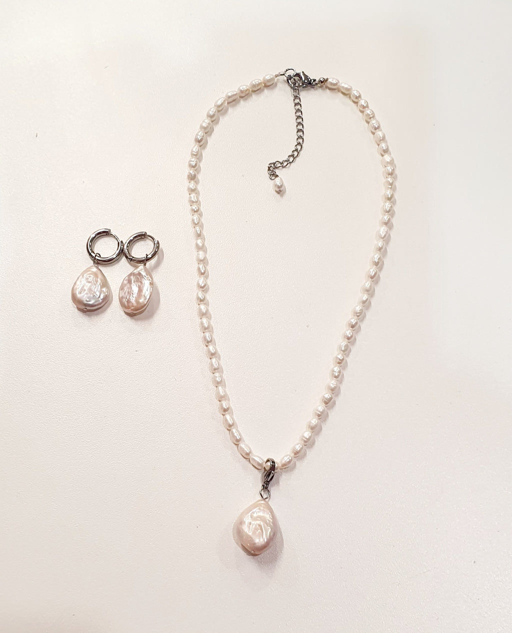 De JES Original Princess Barok is een ode aan natuurlijke elegantie en vrouwelijke kracht.
Deze artisanale zoetwaterparel set werd met de hand samengesteld uit zorgvuldig geselecteerde parels, elk met een eigen vorm, glans en karakter. Geen twee parels zijn identiek — precies daarin schuilt haar schoonheid.


De ketting bestaat uit 68 echte zoetwaterparels, harmonieus geregen tot een verfijnde streng. Centraal hangt een barokke parel, puur en expressief, die afneembaar is via een discreet slotje. Zo draagt 