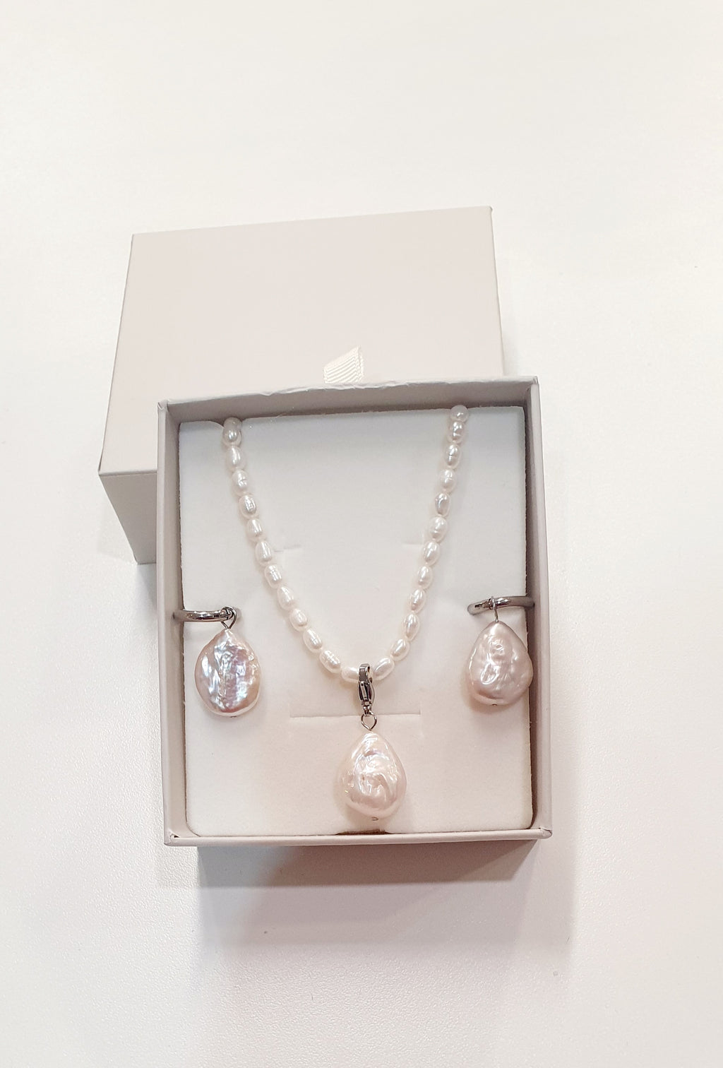 De JES Original Princess Barok is een ode aan natuurlijke elegantie en vrouwelijke kracht.
Deze artisanale zoetwaterparel set werd met de hand samengesteld uit zorgvuldig geselecteerde parels, elk met een eigen vorm, glans en karakter. Geen twee parels zijn identiek — precies daarin schuilt haar schoonheid.


De ketting bestaat uit 68 echte zoetwaterparels, harmonieus geregen tot een verfijnde streng. Centraal hangt een barokke parel, puur en expressief, die afneembaar is via een discreet slotje. Zo draagt 